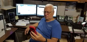 Charles at his desk looking confused about a call on his cellphone